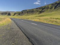 a empty road in an open field with mountains in the background and a sky filled sky