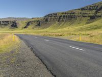 a empty road in an open field with mountains in the background and a sky filled sky