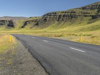 a empty road in an open field with mountains in the background and a sky filled sky