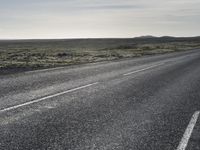 the person in the middle of the empty road and a lone motorcycle is shown in the background