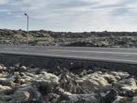 the road next to the lava formations in the mountains is empty and full of snow