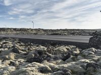 the road next to the lava formations in the mountains is empty and full of snow