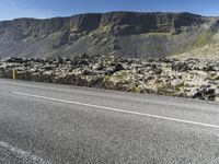 two people are on the side of a road riding motorcycles, with mountains in the distance