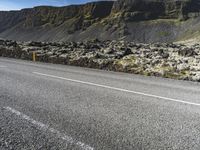 two people are on the side of a road riding motorcycles, with mountains in the distance