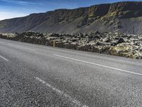 two people are on the side of a road riding motorcycles, with mountains in the distance