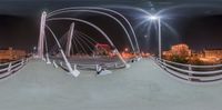 view of a bridge across a city street at night from the bottom and a couple of poles to the side