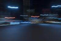 cars speeding down the road in a blurry picture at night time with lights streaking on them