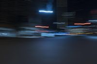 cars speeding down the road in a blurry picture at night time with lights streaking on them