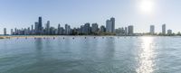 a view of a city skyline over a lake from the beach and pier with several boats