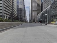 a paved road in the city with tall buildings around it and people walking down it