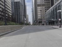 a paved road in the city with tall buildings around it and people walking down it