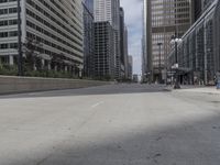 a paved road in the city with tall buildings around it and people walking down it