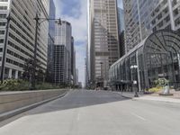 a paved road in the city with tall buildings around it and people walking down it