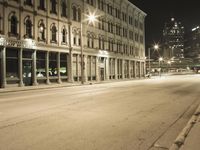 an empty city street with the lights on and cars parked along one side of the road