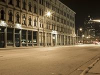 an empty city street with the lights on and cars parked along one side of the road