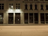 an empty city street with the lights on and cars parked along one side of the road