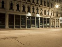 an empty city street with the lights on and cars parked along one side of the road