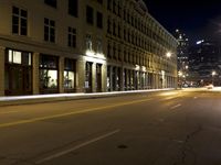 an empty city street with the lights on and cars parked along one side of the road