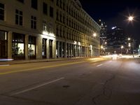 an empty city street with the lights on and cars parked along one side of the road