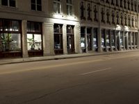 an empty city street with the lights on and cars parked along one side of the road