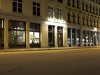 an empty city street with the lights on and cars parked along one side of the road