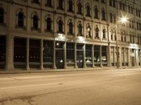 an empty city street with the lights on and cars parked along one side of the road
