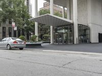 an empty street next to a parking lot with buildings and parked cars on the side of it