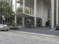an empty street next to a parking lot with buildings and parked cars on the side of it