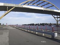 the road is concrete and red, leading to a bridge across water and to a boat