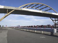 the road is concrete and red, leading to a bridge across water and to a boat