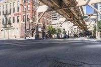 city street with buildings and a bridge above it and pedestrian on the sidewalk next to building