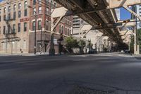 city street with buildings and a bridge above it and pedestrian on the sidewalk next to building