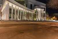 the exterior of a very large building with columns and arches illuminated up at night time