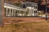 the exterior of a very large building with columns and arches illuminated up at night time