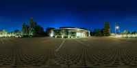 an empty parking lot lit up at night with a circular light structure around the parking