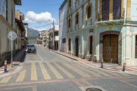 a narrow empty street with some buildings in the background with a motorcycle in front of it