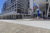 a very large building with many windows and a car parking lot next to it is on the other side of the street