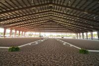 the inside of an arena with stalls and seats on both sides of it and the floor is covered in dirt