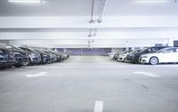 a group of cars sit in the parking lot in an indoor space with white walls