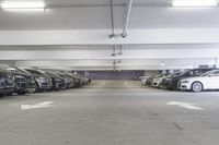 a group of cars sit in the parking lot in an indoor space with white walls