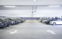 a group of cars sit in the parking lot in an indoor space with white walls