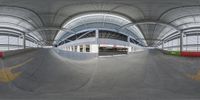 an inside view of an indoor skate park with concrete floor and roofing, including the ceiling and ramp