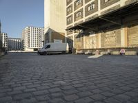 white van parked in front of a large industrial building and two towers on either side