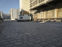 white van parked in front of a large industrial building and two towers on either side