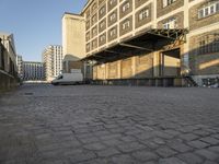 white van parked in front of a large industrial building and two towers on either side