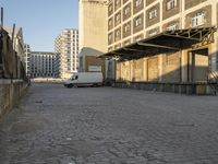 white van parked in front of a large industrial building and two towers on either side