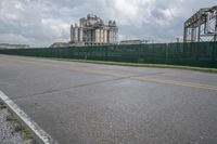 a view of the side of an empty road with a fence to protect it from the rain