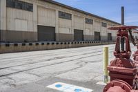 a fire hydrant sitting outside of a warehouse with a red stop sign next to it