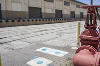 a fire hydrant sitting outside of a warehouse with a red stop sign next to it