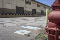 a fire hydrant sitting outside of a warehouse with a red stop sign next to it